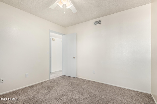 empty room with ceiling fan, light colored carpet, and a textured ceiling