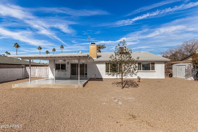 rear view of house with a storage shed and a patio area