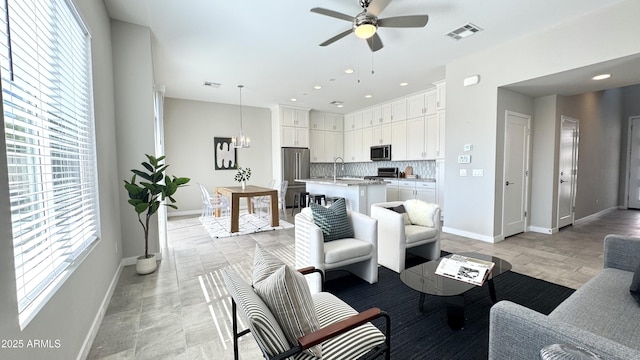 living room with sink and ceiling fan with notable chandelier