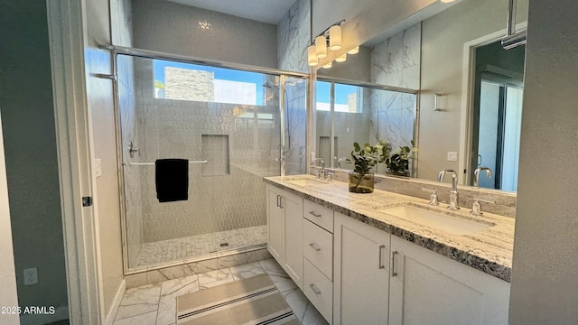 full bathroom with double vanity, marble finish floor, a sink, and a stall shower