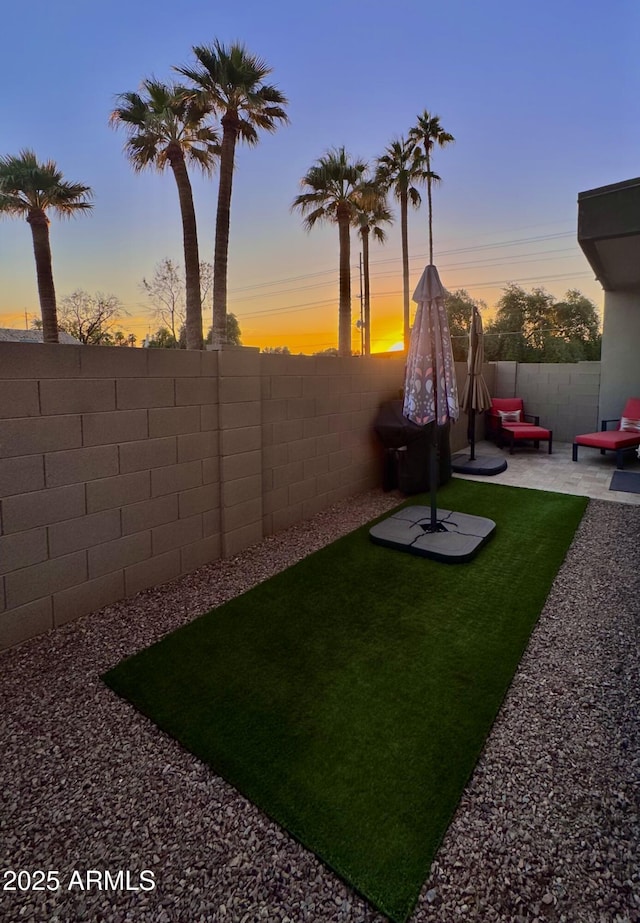 yard at dusk with a fenced backyard and a patio