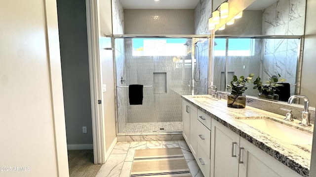 full bath featuring a stall shower, marble finish floor, and a sink