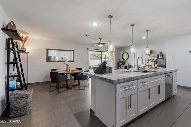 kitchen featuring a center island with sink, sink, ceiling fan, decorative light fixtures, and white cabinetry