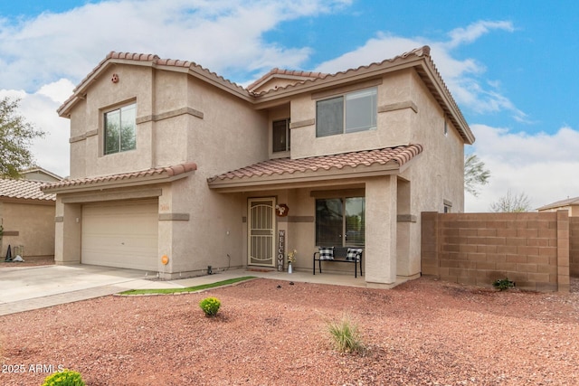 mediterranean / spanish-style house with concrete driveway, a tiled roof, an attached garage, fence, and stucco siding