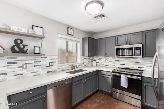 kitchen with gray cabinetry, stainless steel appliances, a sink, visible vents, and open shelves