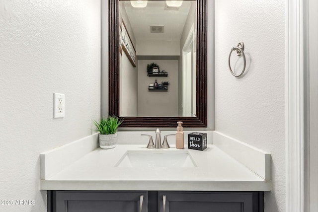 bathroom featuring a textured wall, vanity, and visible vents