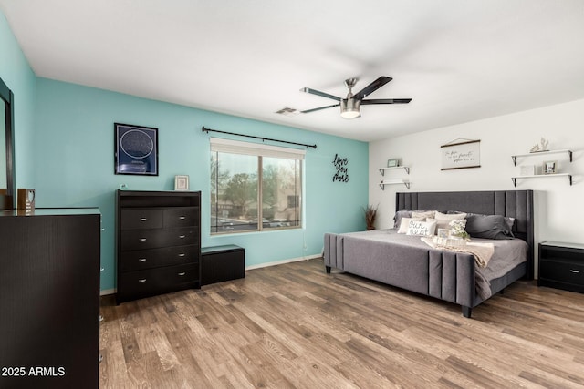 bedroom with baseboards, ceiling fan, visible vents, and wood finished floors