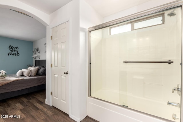 ensuite bathroom with bath / shower combo with glass door, ensuite bath, and wood finished floors