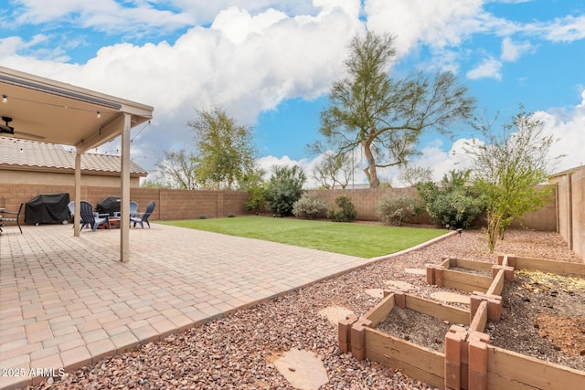 view of patio / terrace with a fenced backyard, a vegetable garden, a ceiling fan, and area for grilling