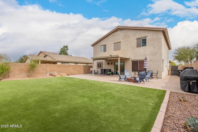 back of property with a fenced backyard, a fire pit, a yard, stucco siding, and a patio area