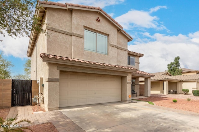 view of front of property featuring stucco siding, an attached garage, a gate, driveway, and a tiled roof