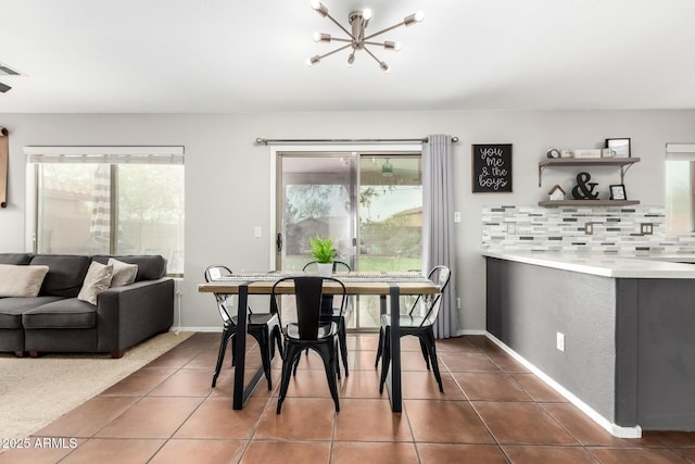 dining area with a chandelier, dark tile patterned flooring, visible vents, and baseboards