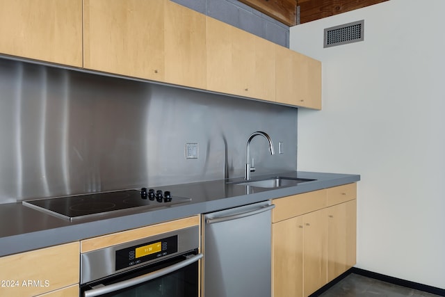 kitchen featuring light brown cabinets, sink, stainless steel oven, and black electric cooktop