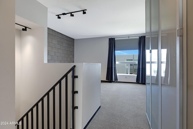 hallway featuring track lighting and carpet