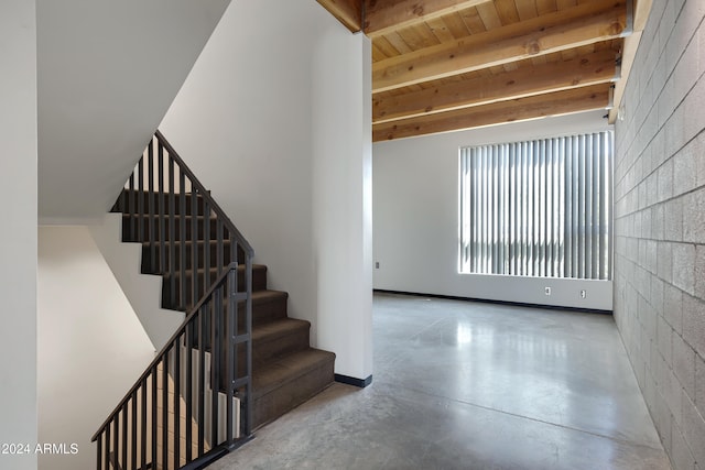 stairs featuring wooden ceiling, beamed ceiling, and concrete floors