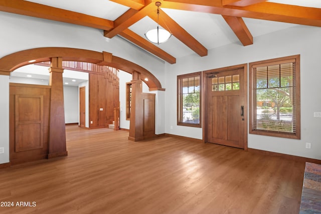 entryway with ornate columns, lofted ceiling with beams, and light wood-type flooring