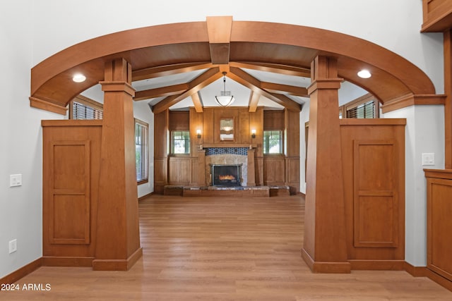 unfurnished living room with vaulted ceiling with beams, light hardwood / wood-style floors, and a premium fireplace