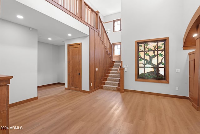 unfurnished living room featuring a towering ceiling and light wood-type flooring