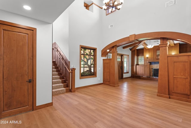 entrance foyer with a chandelier, a towering ceiling, and light wood-type flooring