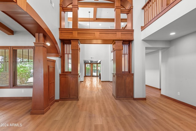 interior space with a high ceiling, decorative columns, plenty of natural light, and light hardwood / wood-style floors