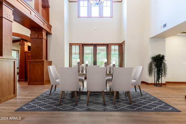 dining room with a towering ceiling and wood-type flooring