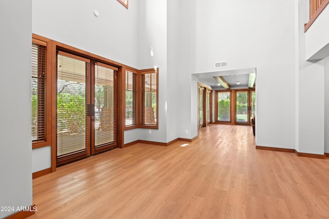 entryway with light wood-type flooring, a high ceiling, and french doors