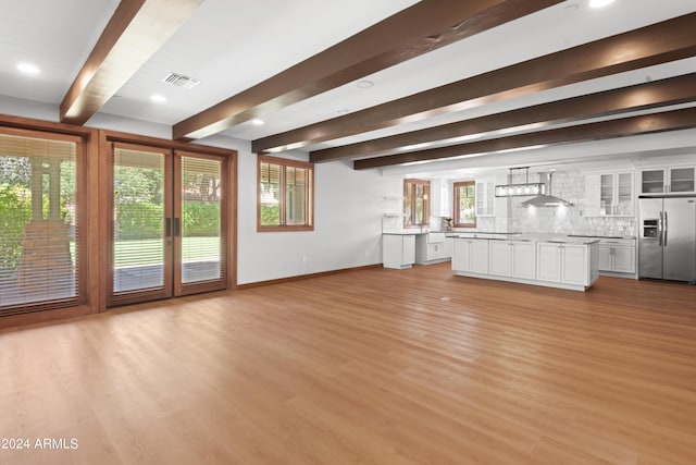 unfurnished living room with beamed ceiling and light hardwood / wood-style floors