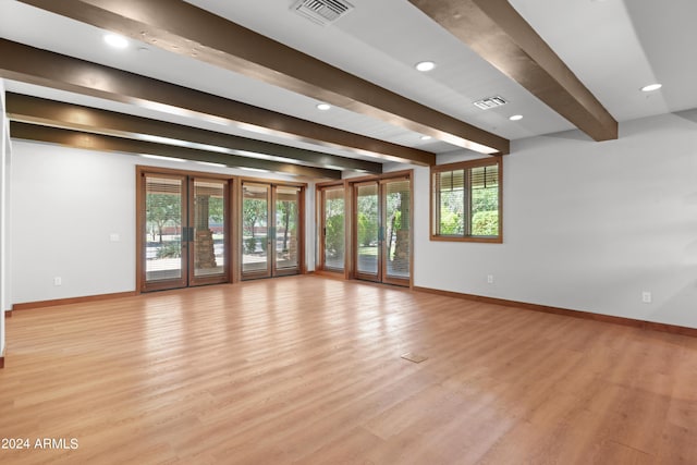 unfurnished living room featuring beam ceiling and light wood-type flooring