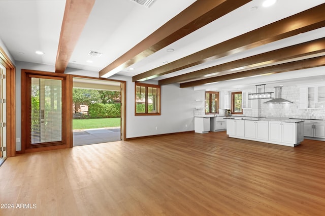 unfurnished living room with beamed ceiling and light hardwood / wood-style floors