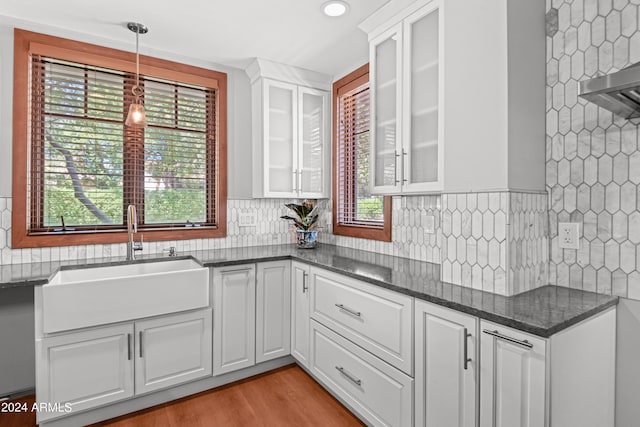 kitchen featuring decorative light fixtures, dark stone countertops, white cabinetry, and sink