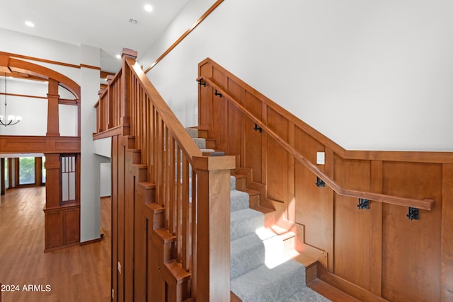 stairs with hardwood / wood-style flooring and a notable chandelier