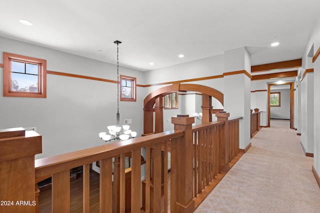 hallway with light colored carpet and an inviting chandelier