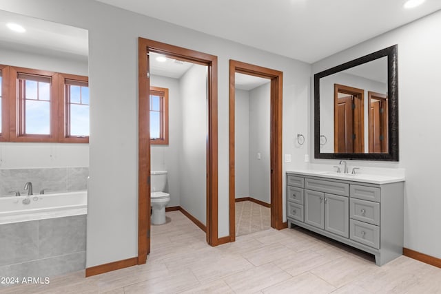 bathroom featuring tile patterned flooring, vanity, a relaxing tiled tub, and toilet