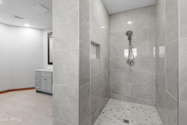 bathroom with a tile shower and vanity