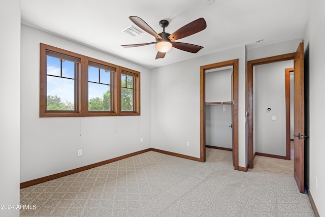 unfurnished bedroom with ceiling fan, light colored carpet, a spacious closet, and a closet