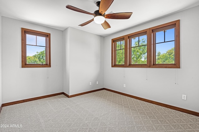 spare room with light colored carpet, plenty of natural light, and ceiling fan