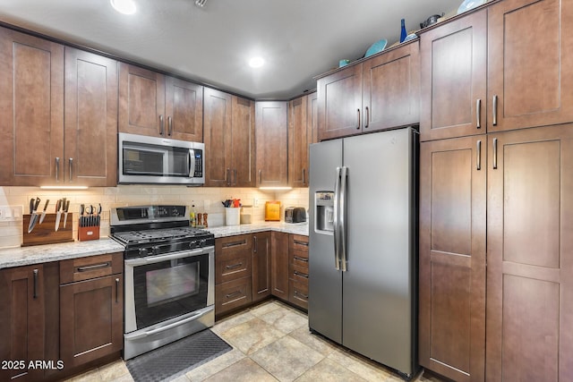 kitchen with appliances with stainless steel finishes, recessed lighting, light stone countertops, and tasteful backsplash