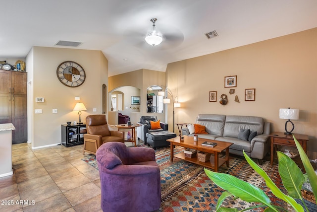 living room featuring vaulted ceiling, light tile patterned flooring, arched walkways, and visible vents