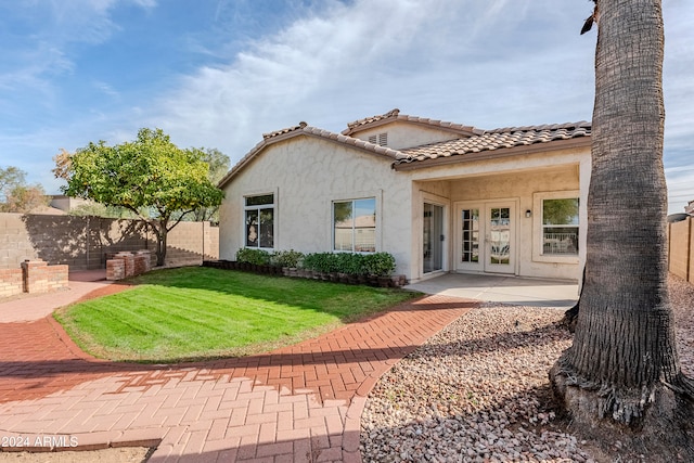 mediterranean / spanish house featuring french doors and a front lawn