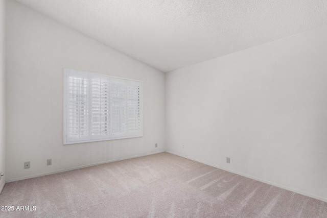 unfurnished room with vaulted ceiling, a textured ceiling, and carpet