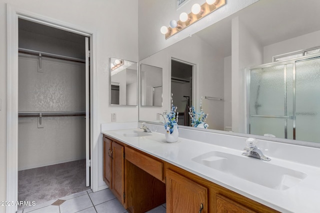 bathroom featuring a stall shower, tile patterned flooring, a sink, and a spacious closet