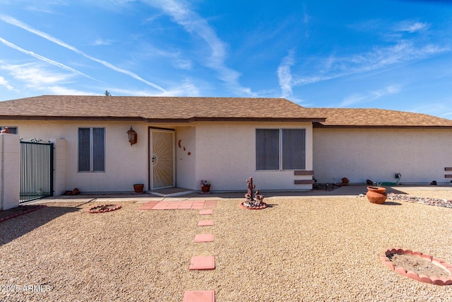 ranch-style house with a patio area, roof with shingles, and stucco siding