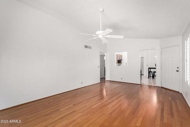 unfurnished living room with ceiling fan, wood finished floors, visible vents, and lofted ceiling