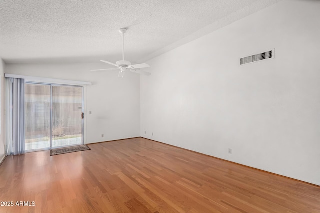 empty room with ceiling fan, a textured ceiling, visible vents, light wood-style floors, and vaulted ceiling