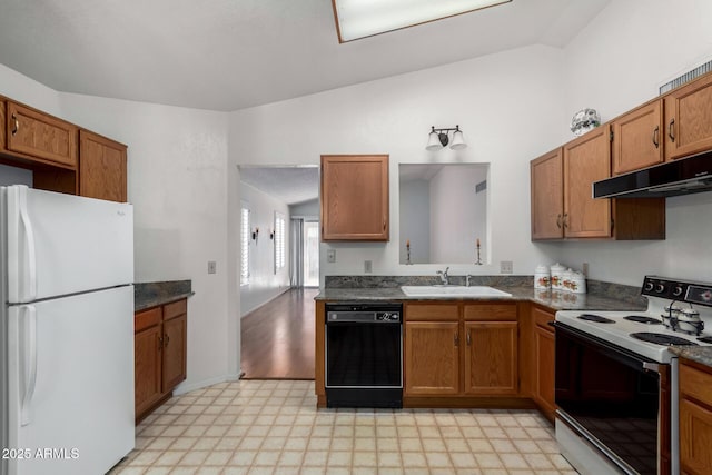 kitchen featuring electric range, a sink, black dishwasher, freestanding refrigerator, and dark countertops