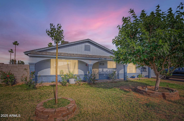 view of front of house featuring a lawn, fence, and stucco siding