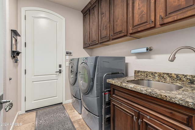 laundry area with washing machine and clothes dryer, sink, and cabinets