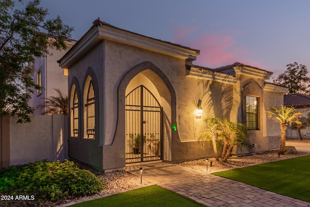 exterior entry at dusk featuring a lawn