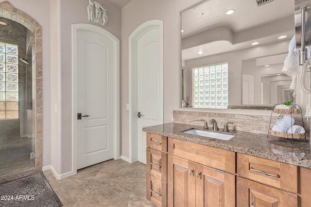 bathroom with vanity, a shower with shower door, and backsplash