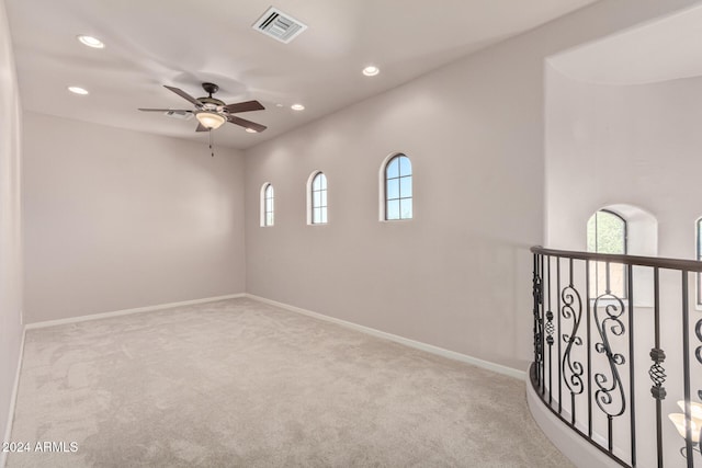 spare room featuring light carpet, ceiling fan, and a healthy amount of sunlight